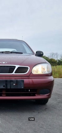 the front end of a maroon car parked in a parking lot