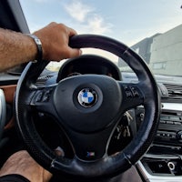 a man is holding the steering wheel of a bmw