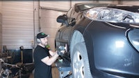 a man working on a black car in a garage